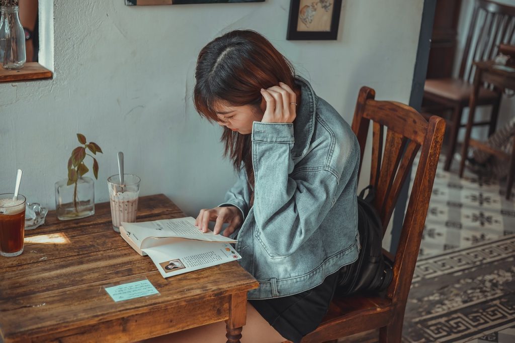 一位女子坐在咖啡廳閱讀書籍圖